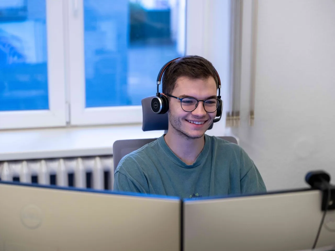 Lennart Leopold sitzt am Schreibtisch und und hat ein Headset auf. Er ist in einem Kundenservicegespräch.
